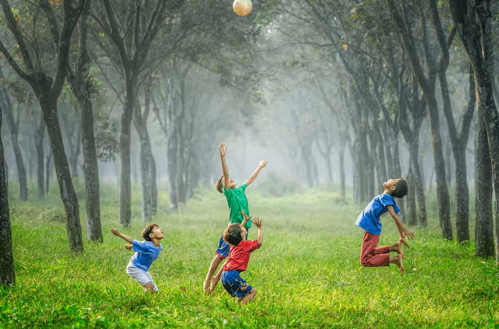 a group of kids playing with a ball in a park